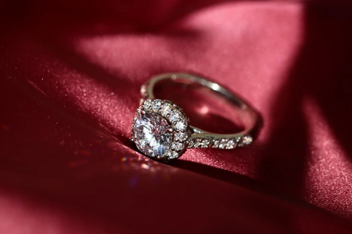 silver diamond ring on red textile